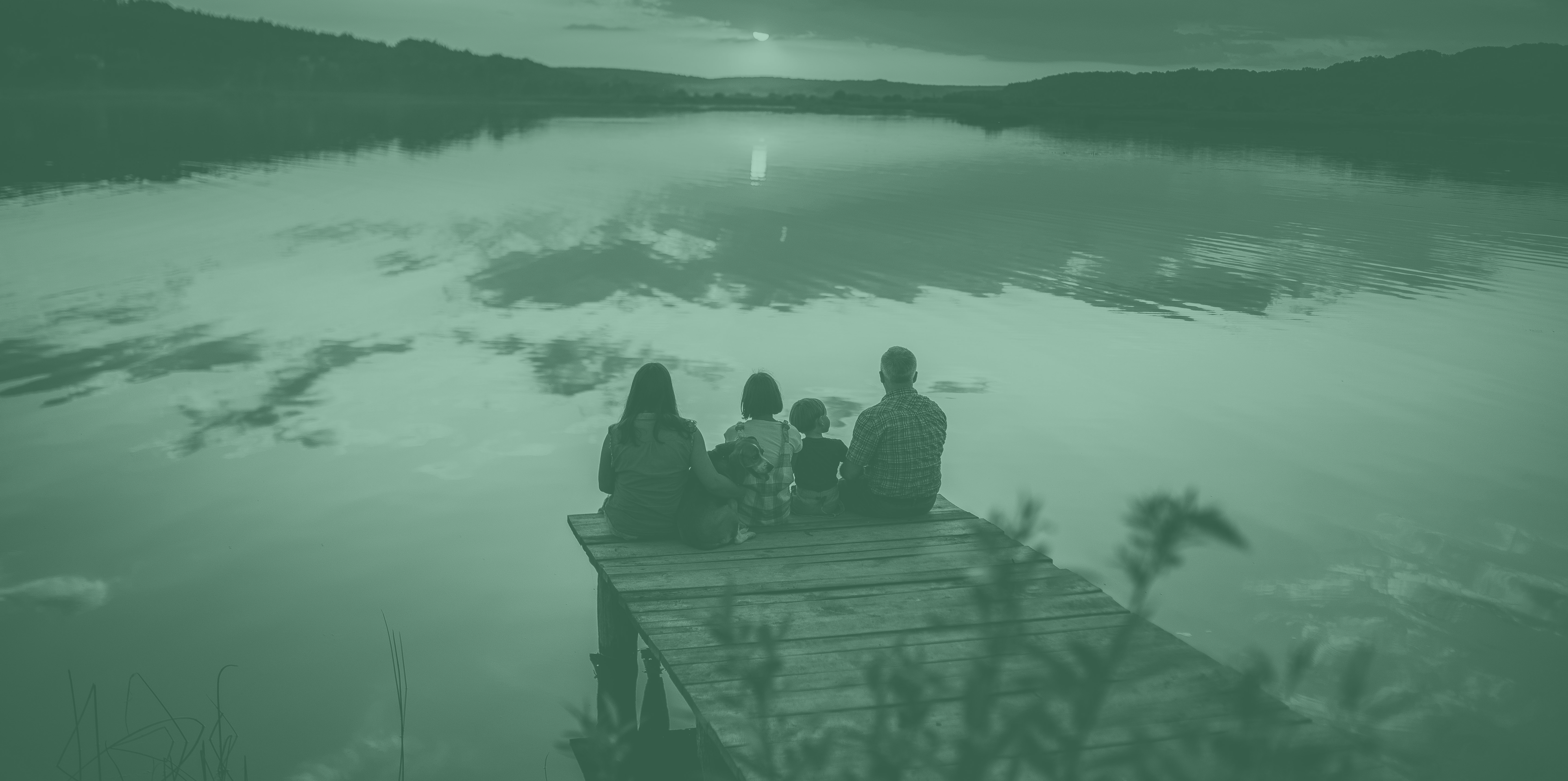 family sitting on a pier at sunset